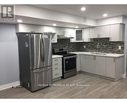 A modern kitchen with a stainless steel refrigerator and white cabinets.