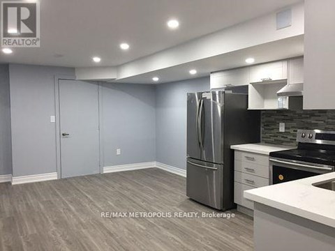 A kitchen with a refrigerator, stove, and cabinets.