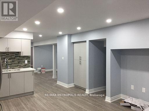 A room with a sink and cabinets in a building under construction.