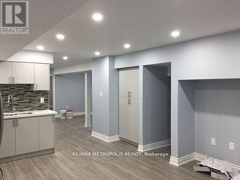 A room with a sink and cabinets in a building under construction.