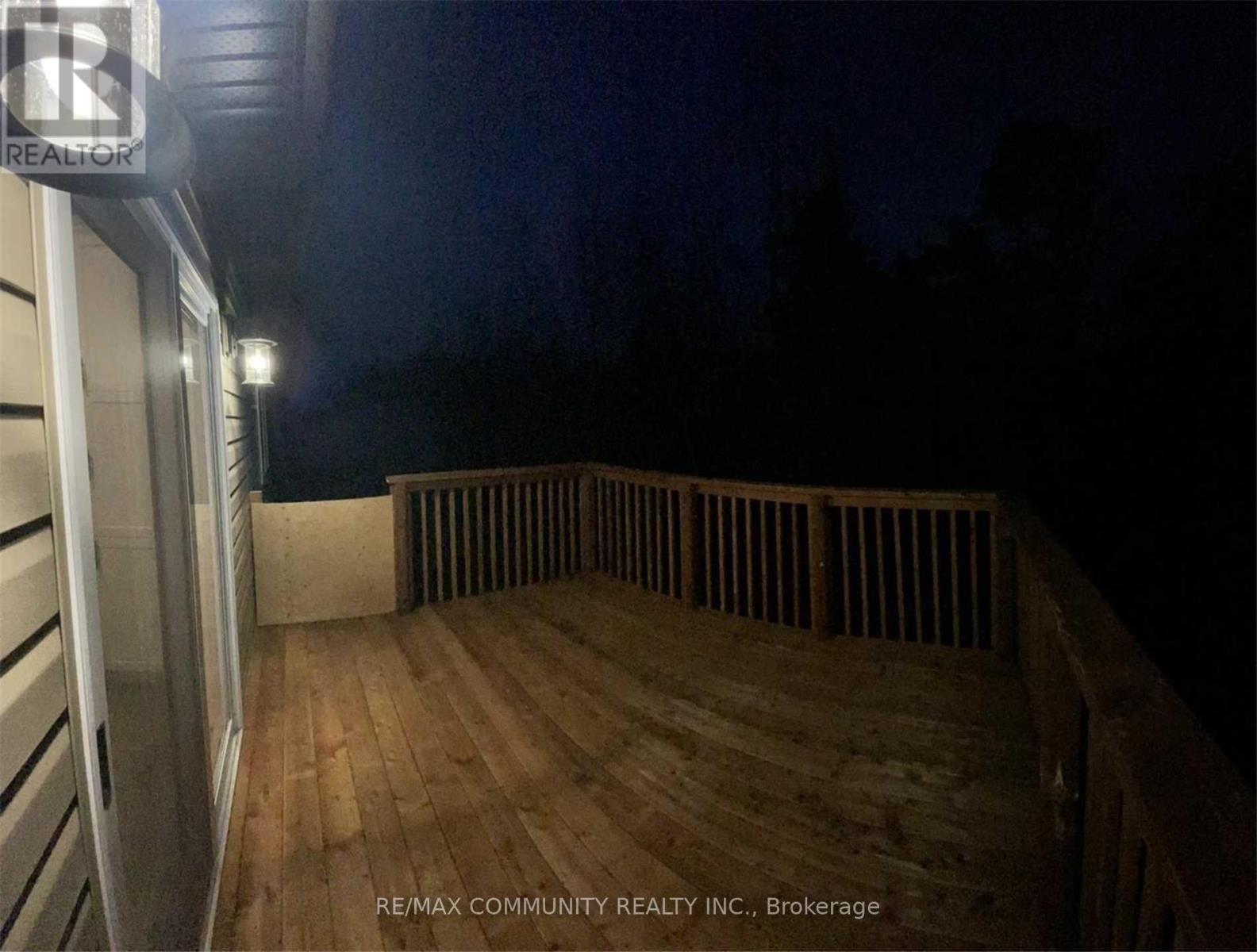 A wooden deck with a railing and a building in the background.