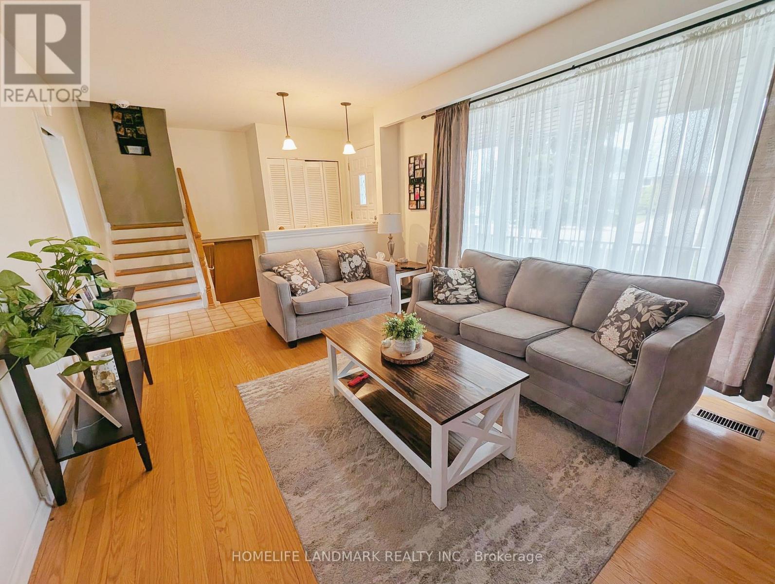 A living room with a grey couch, a coffee table, and a staircase.