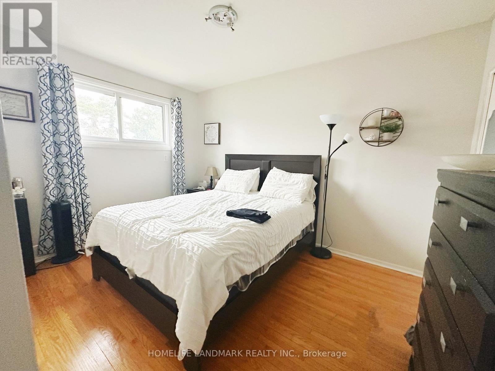 A bedroom with a bed, nightstand, and a window with curtains.