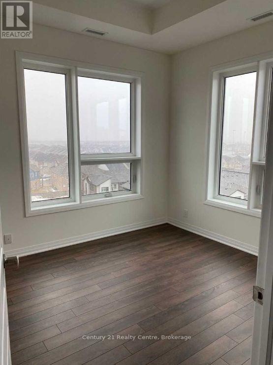 A room with wooden floors and two windows overlooking a cityscape.