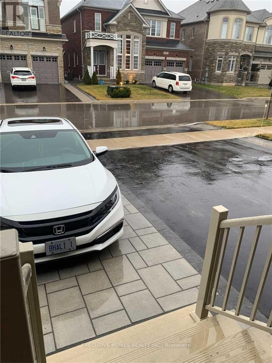 A white Honda car is parked on a wet street.