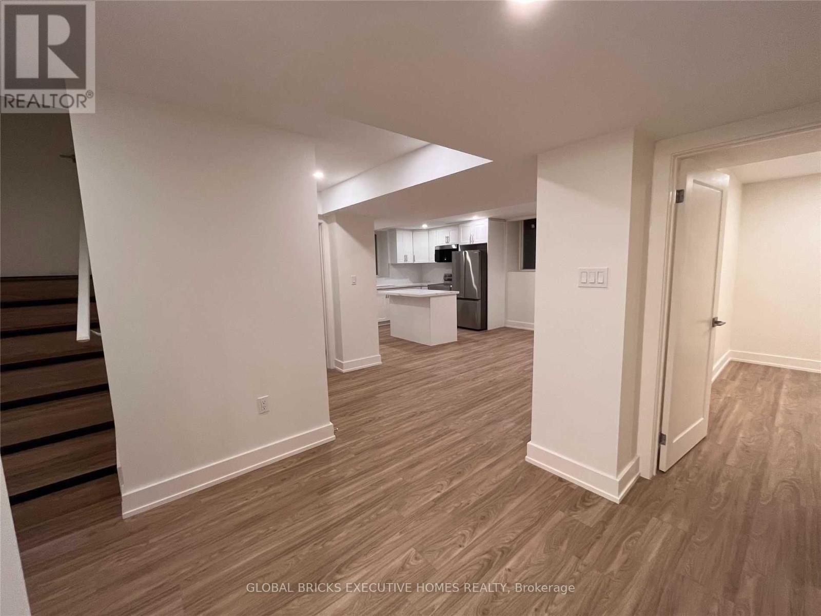 A spacious room with wooden flooring and white walls.