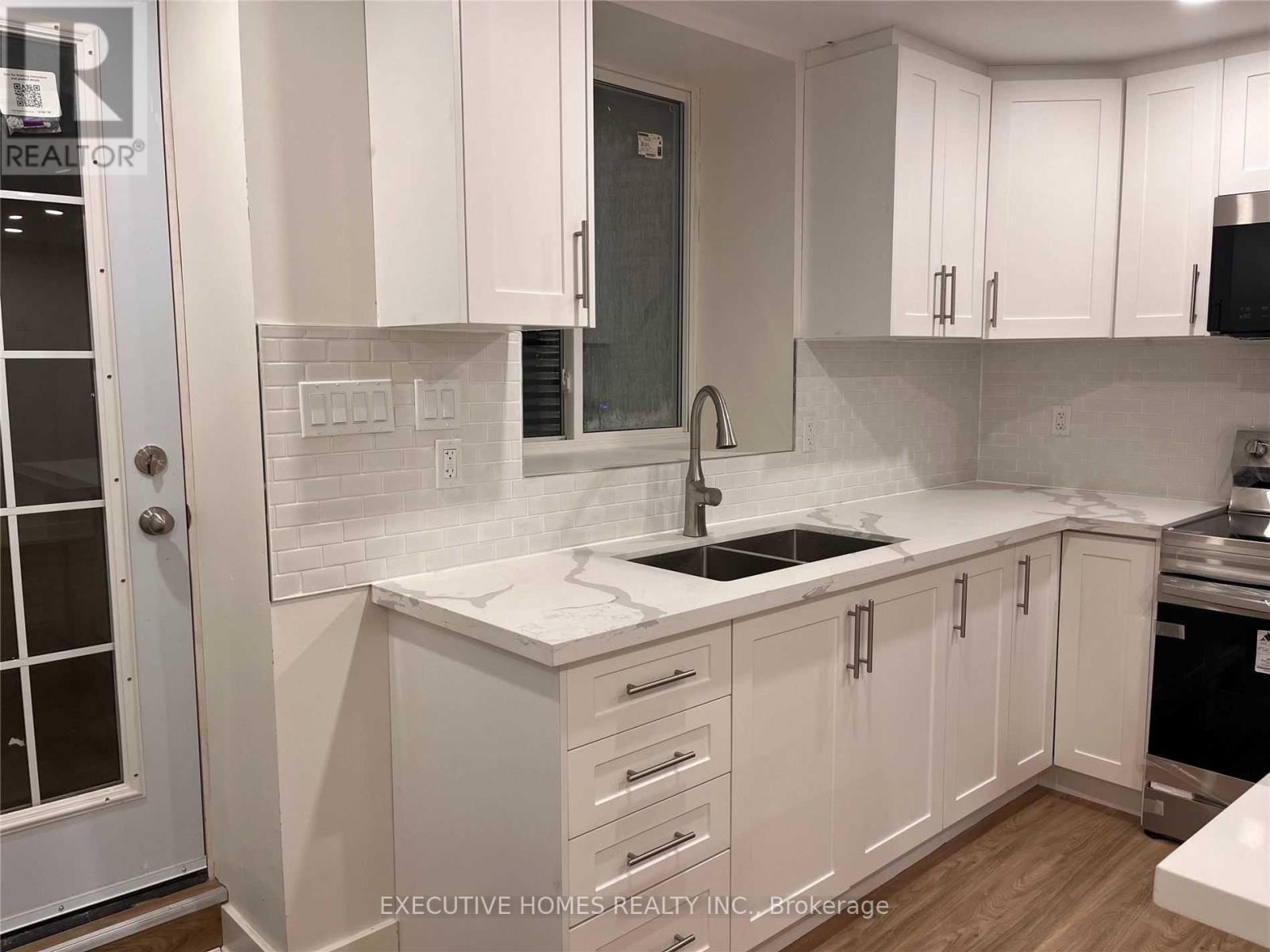 A kitchen with white cabinets and a marble countertop.