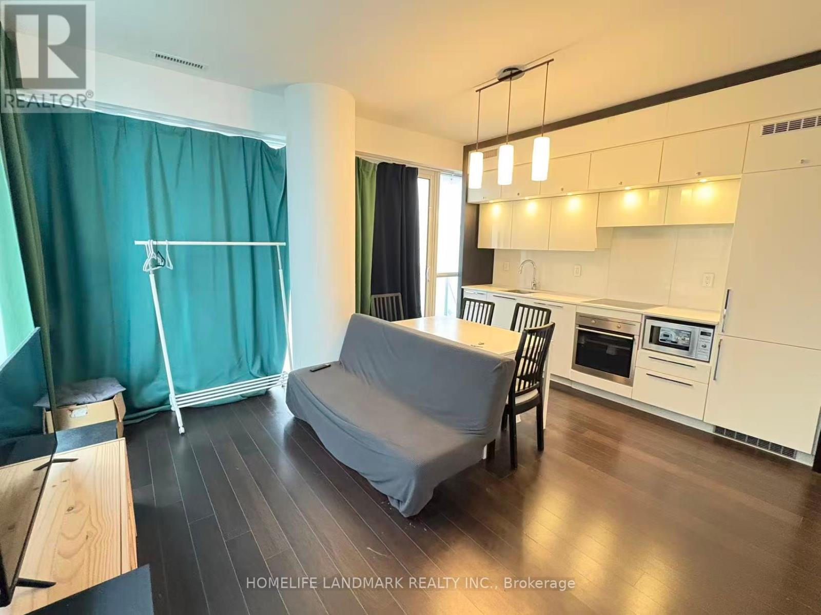 A modern kitchen with white cabinets and a grey sofa.