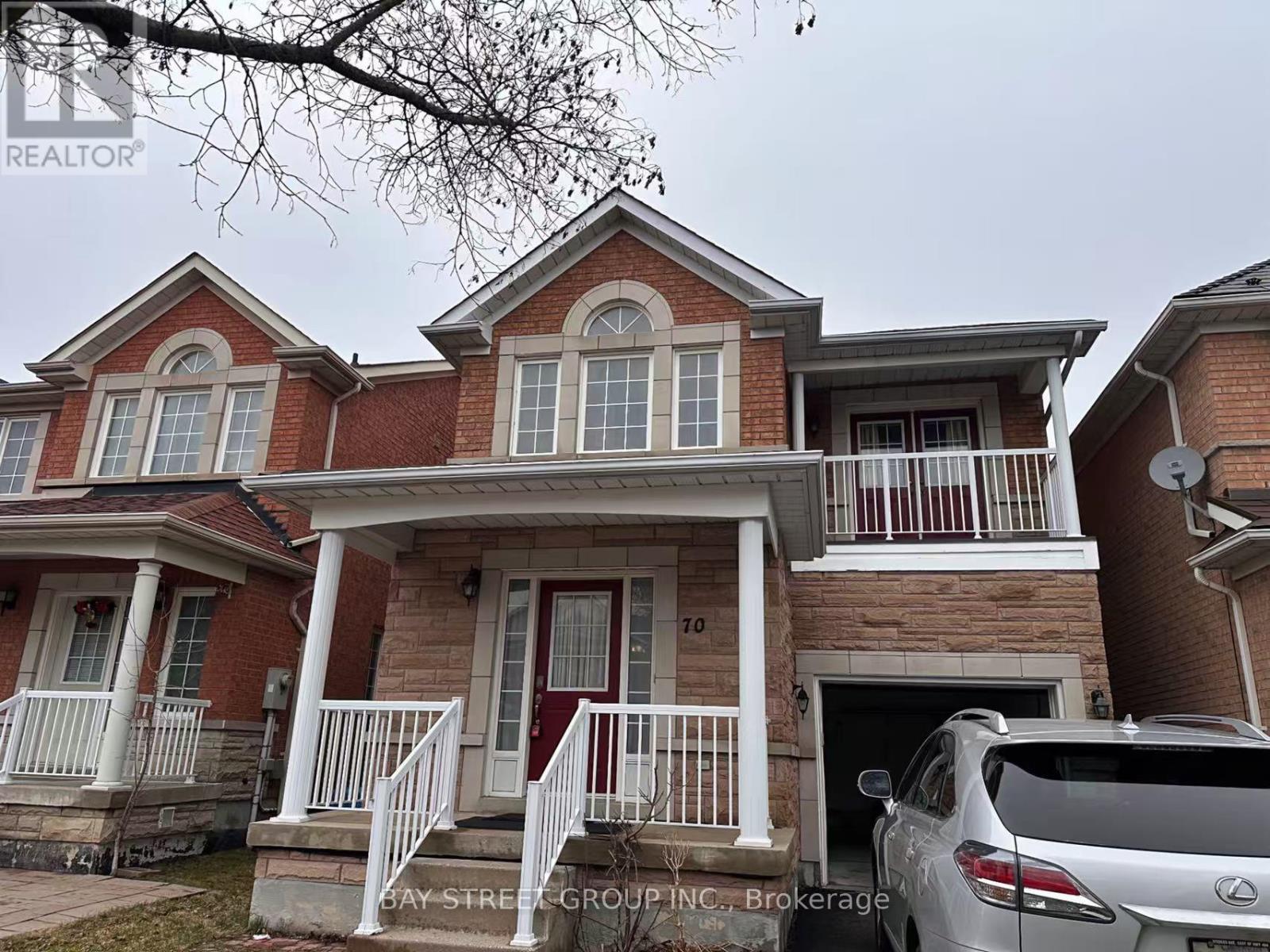 A two-story brick house with a car parked in front.
