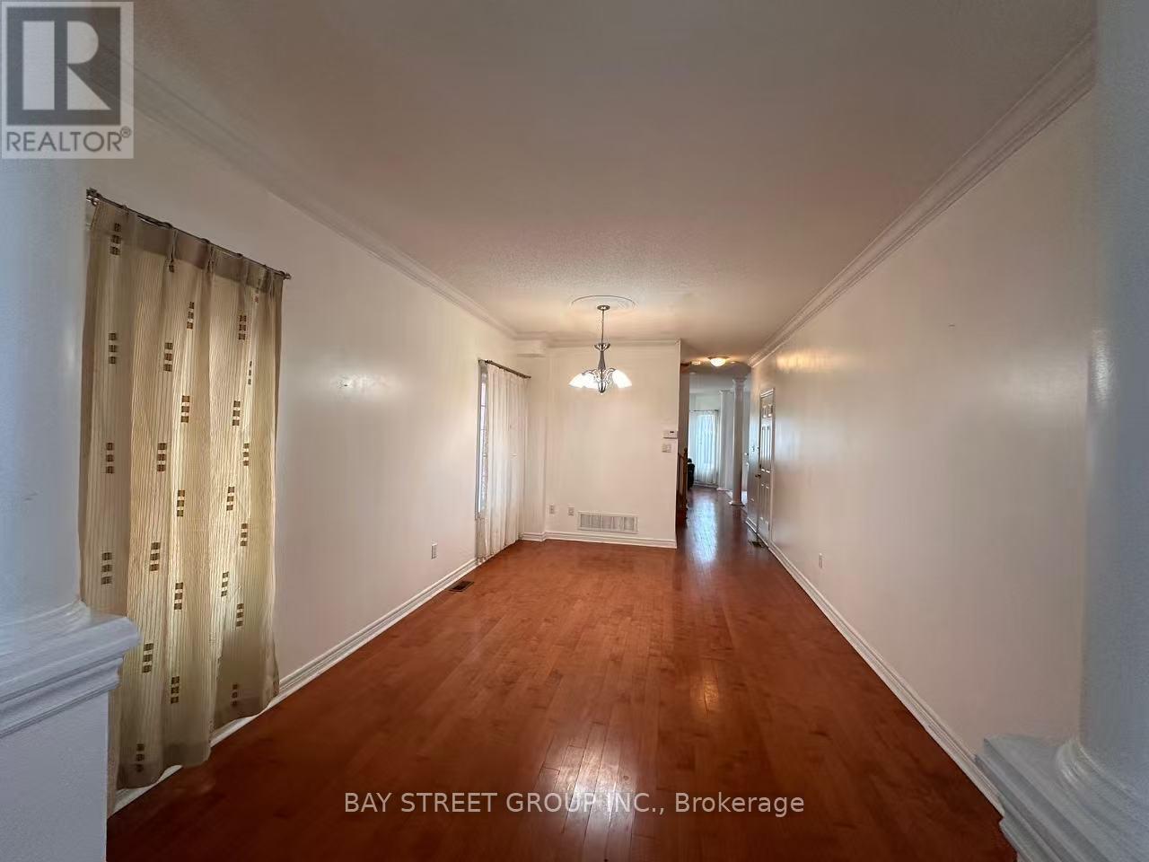 A long hallway with a white wall and wooden floor.