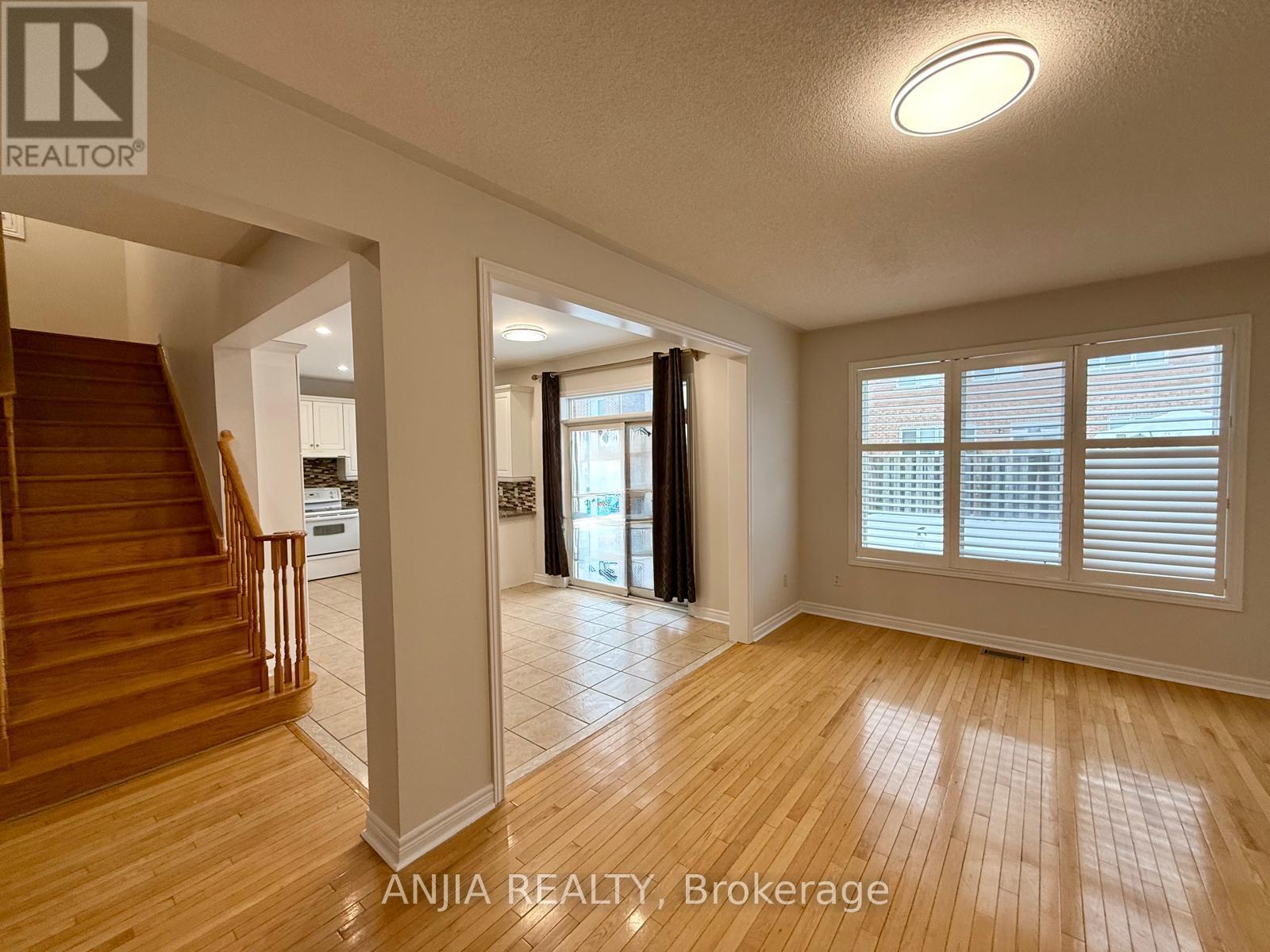 A spacious room with wooden flooring and a staircase leading to another level.