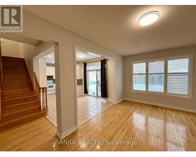 A spacious room with wooden flooring and a staircase leading to another level.