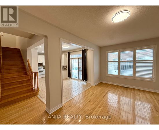 A spacious room with wooden flooring and a staircase leading to another level.