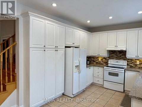 A kitchen with white cabinets and appliances, including a refrigerator, stove, and oven.