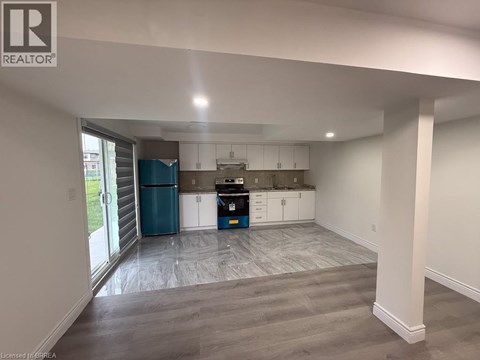 A spacious kitchen with white cabinets and a blue trash bin.