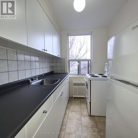 A kitchen with white cabinets and black countertops.