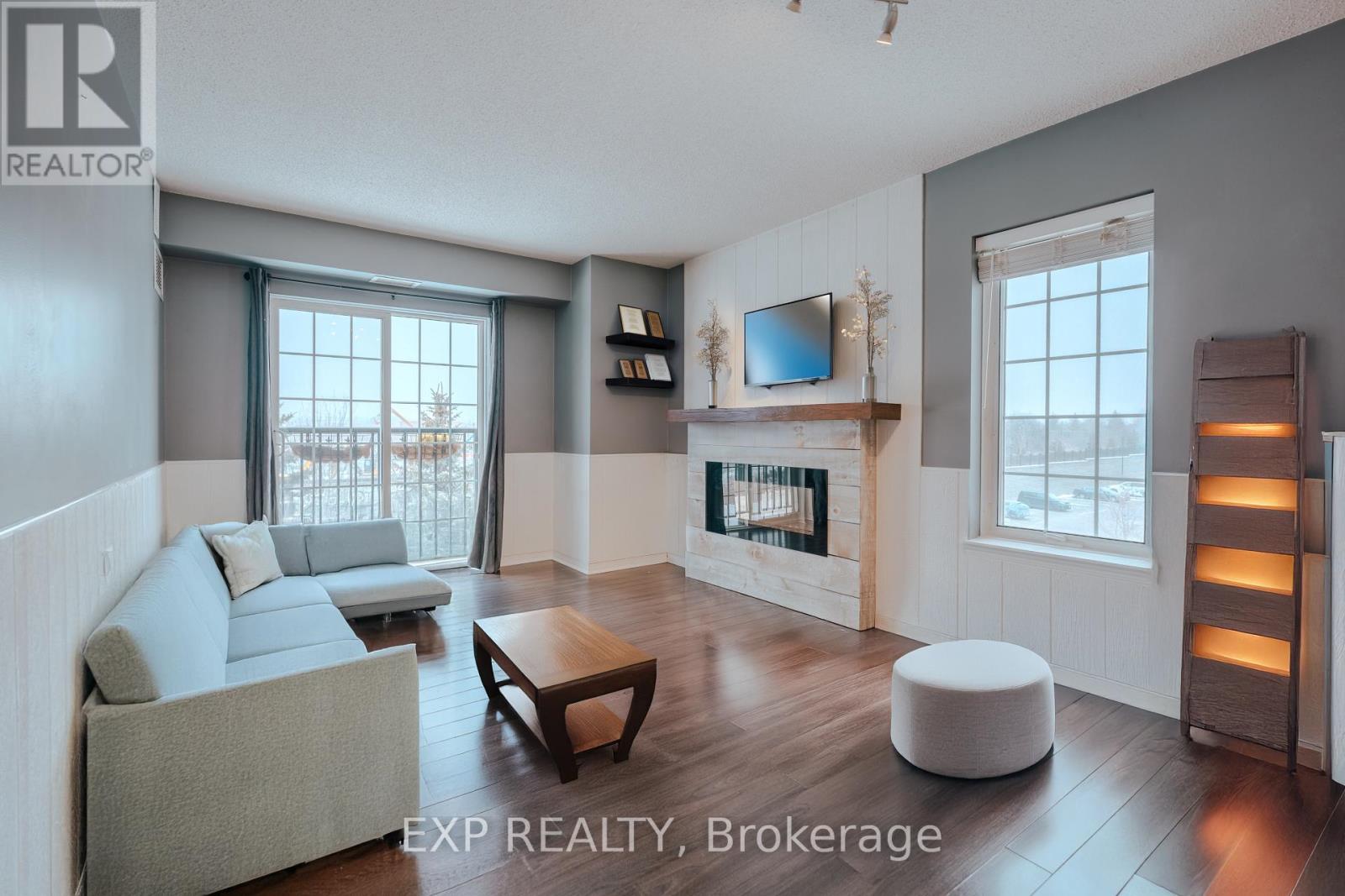 A living room with a grey couch, a wooden coffee table, a fireplace, and a flat screen TV mounted above it.