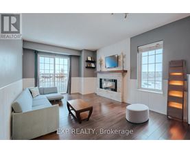 A living room with a grey couch, a wooden coffee table, a fireplace, and a flat screen TV mounted above it.