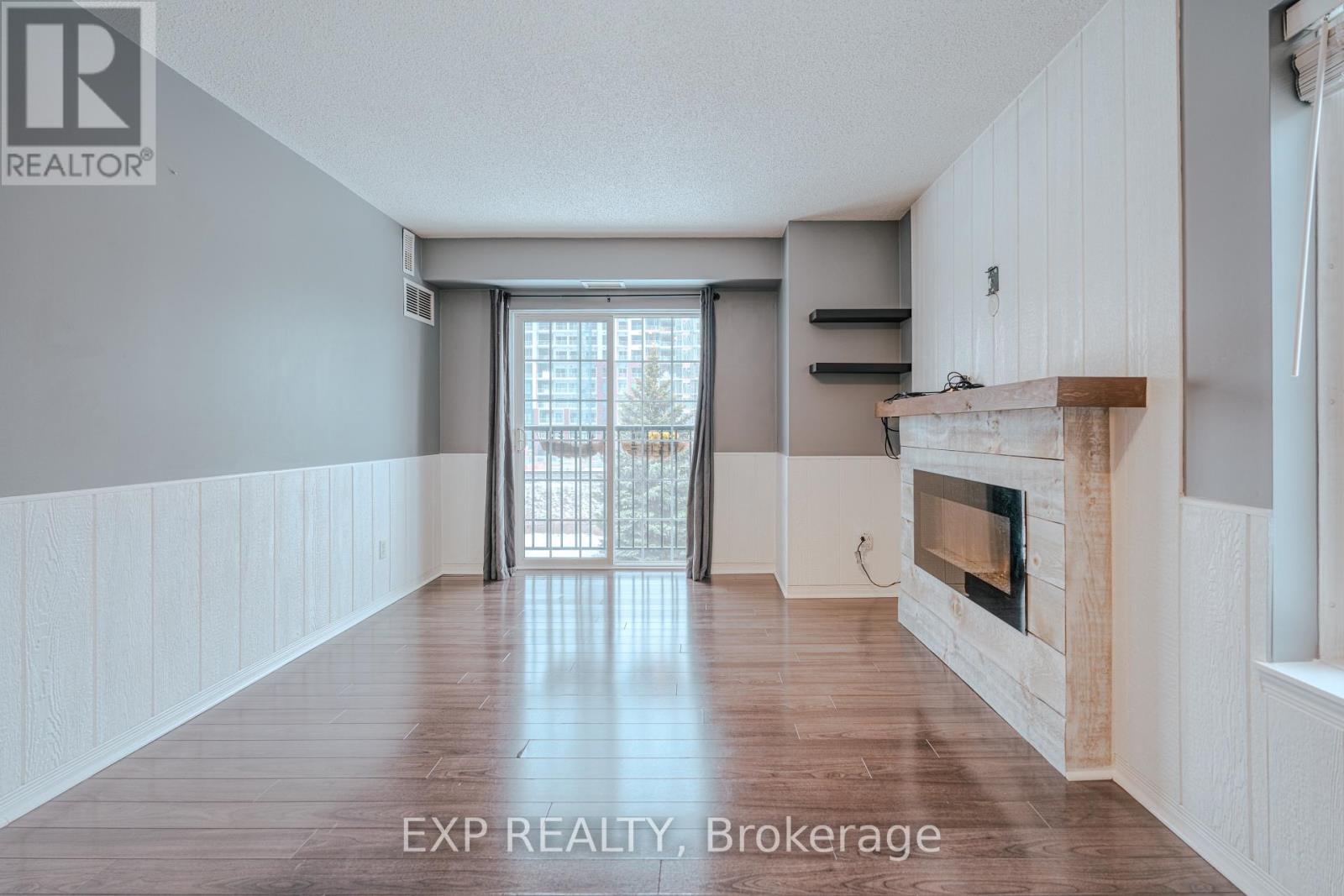 A spacious room with a fireplace and a sliding glass door leading to a balcony.