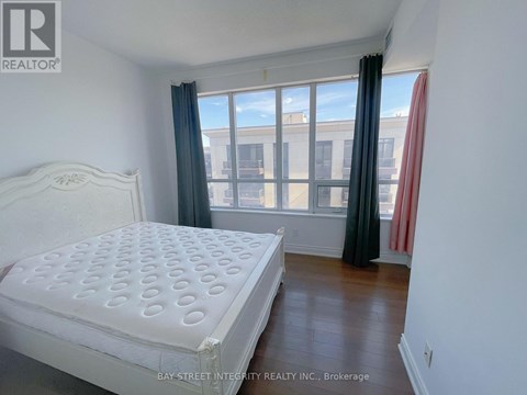 A bedroom with a large bed and a window with curtains.