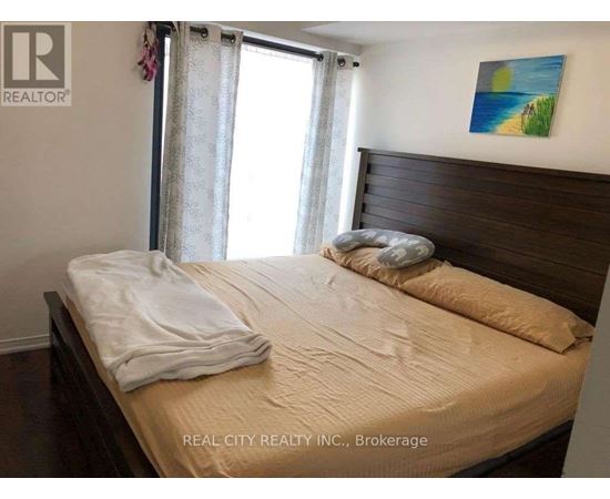 A bedroom with a bed, pillows, and a painting on the wall.