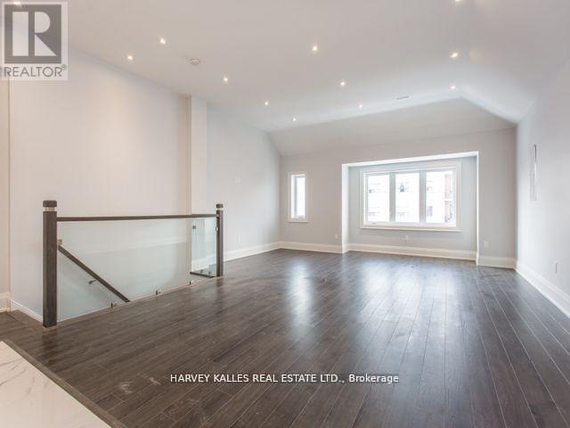 A spacious room with wooden flooring and a glass railing.