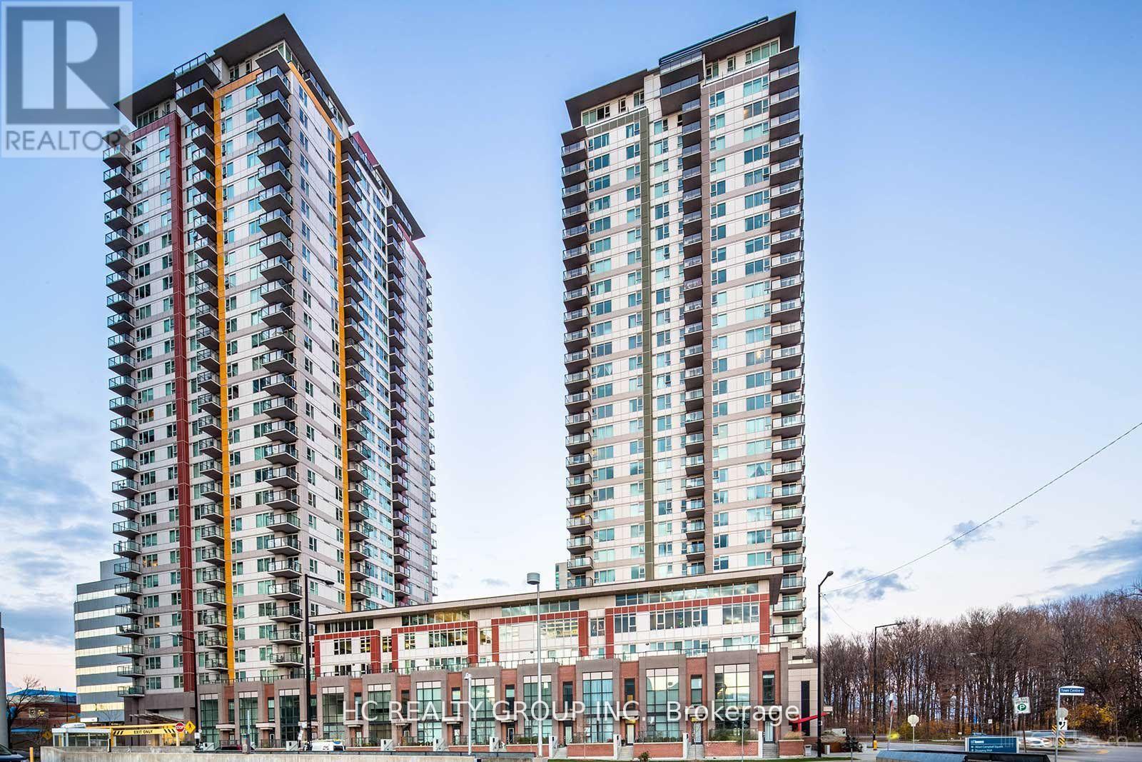 Two tall residential buildings stand next to a building with a glass facade.