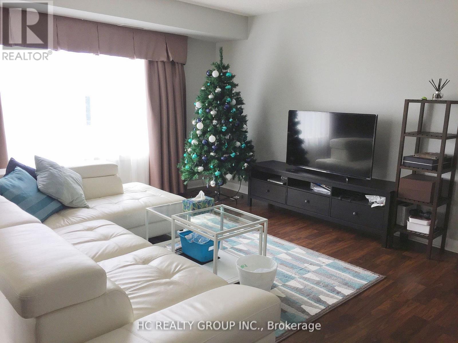 A living room with a Christmas tree and a flat screen TV.
