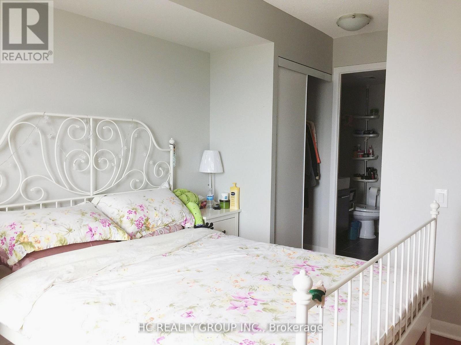A bedroom with a floral bedspread and a white metal bed frame.