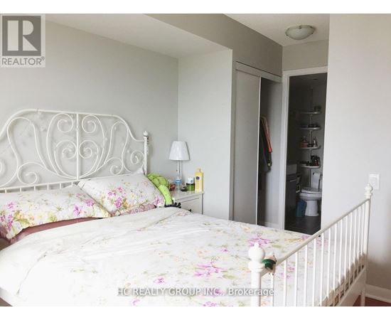 A bedroom with a floral bedspread and a white metal bed frame.