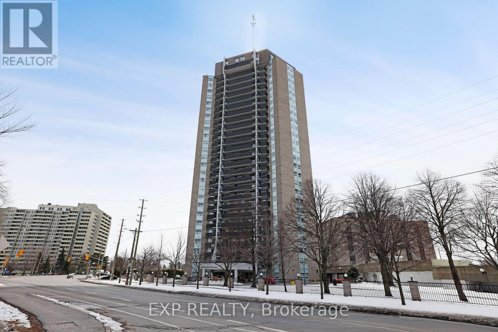 A tall building with a glass facade stands in the middle of a snowy street.