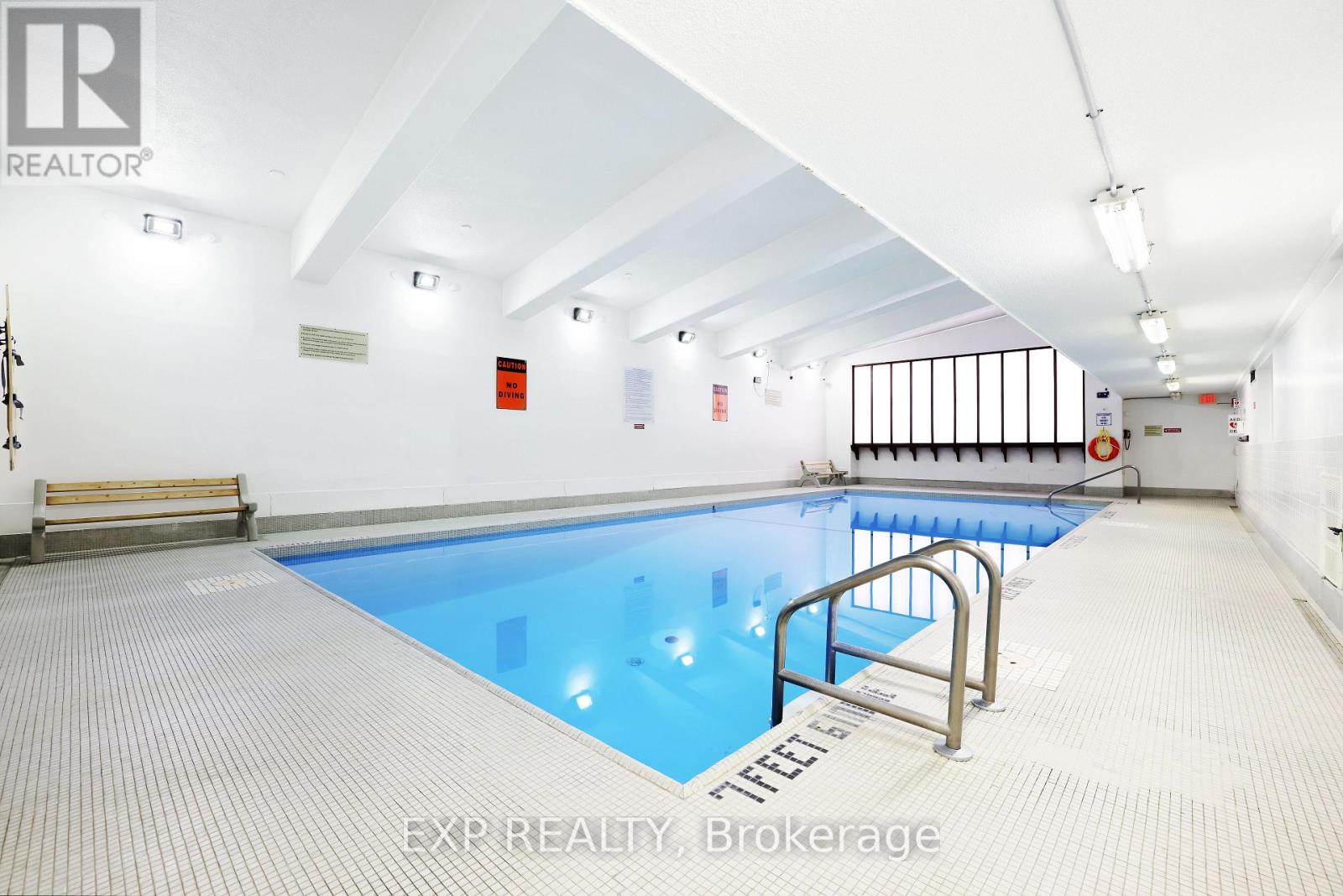A swimming pool inside a building with a bench and a ladder.