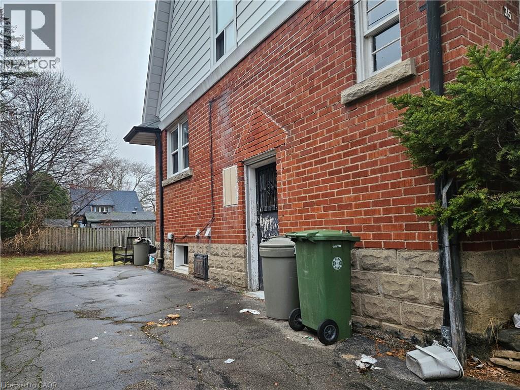 A red brick house with a green trash bin outside.