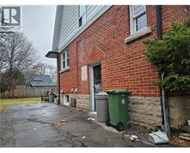 A red brick house with a green trash bin outside.