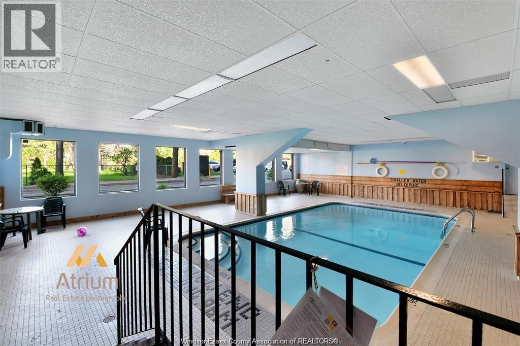 A large indoor swimming pool with a glass barrier and a sign that says "Atrium".