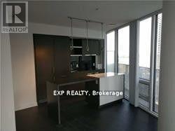 A real estate sign is displayed in a room with a kitchen area.