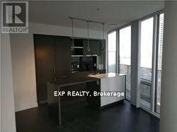 A real estate sign is displayed in a room with a kitchen area.