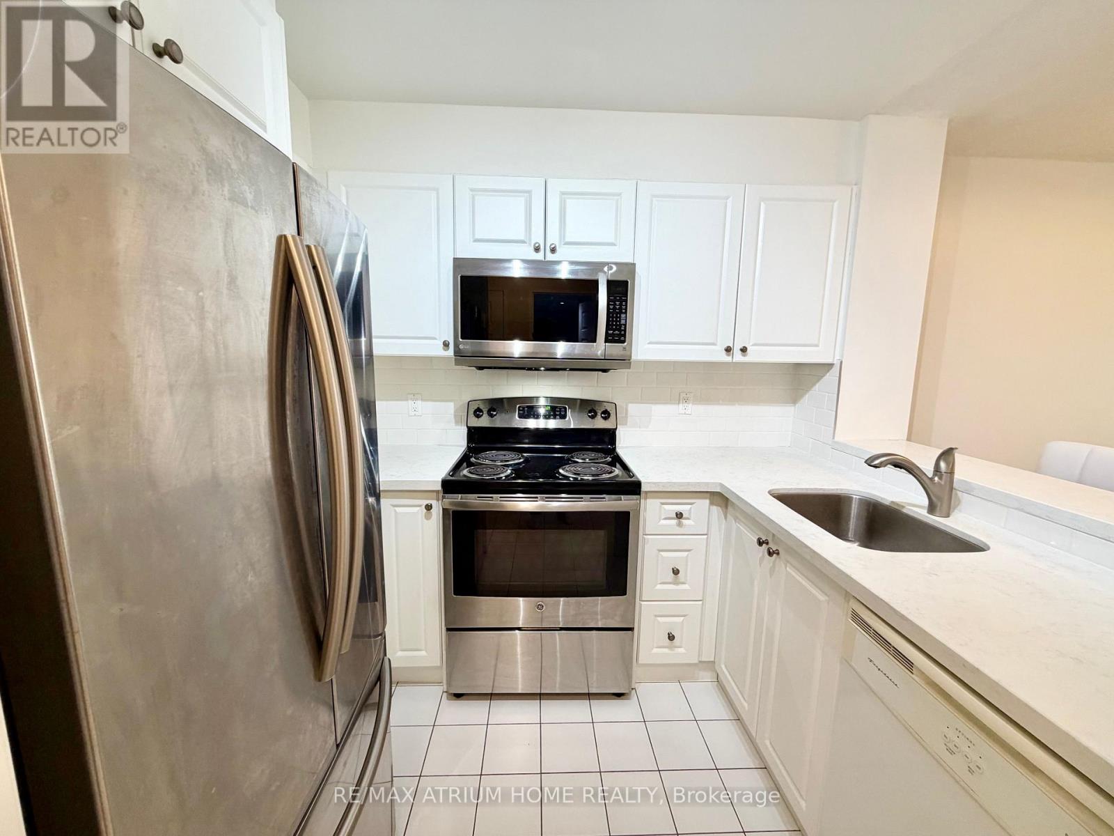 A kitchen with white cabinets and a stainless steel refrigerator.