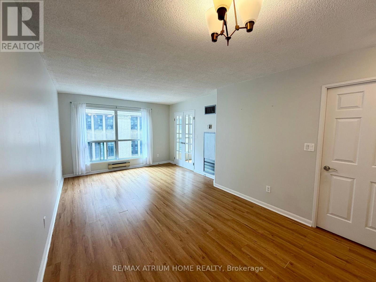 A spacious room with wooden flooring and white walls.