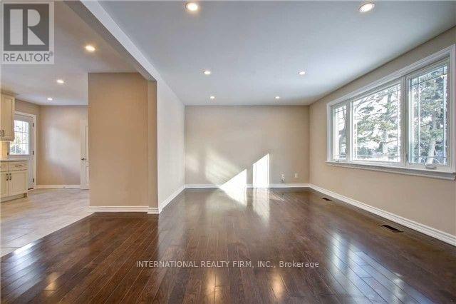 A spacious room with wooden floors and a large window.