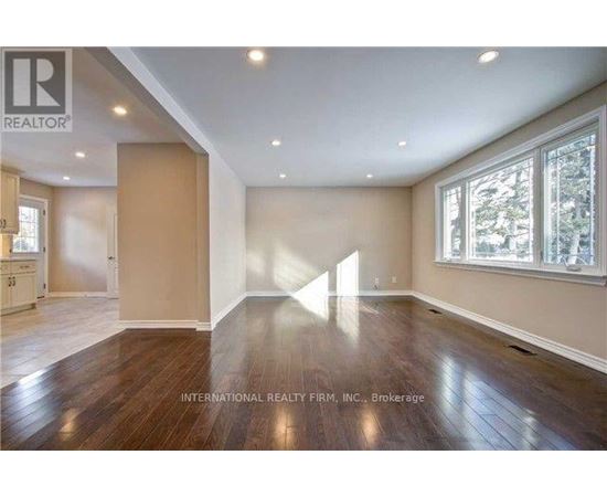 A spacious room with wooden floors and a large window.