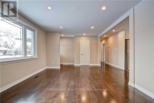 A spacious room with wooden floors and white walls.