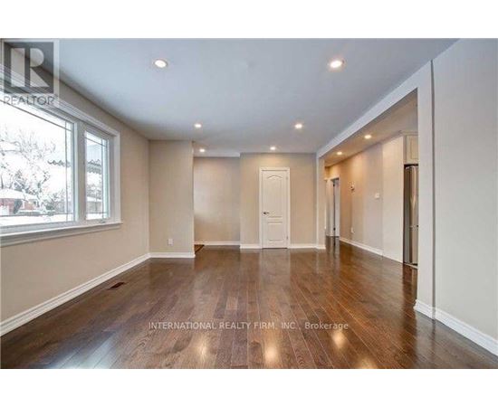 A spacious room with wooden floors and white walls.