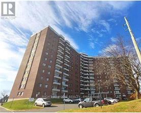 A tall apartment building with cars parked in front.