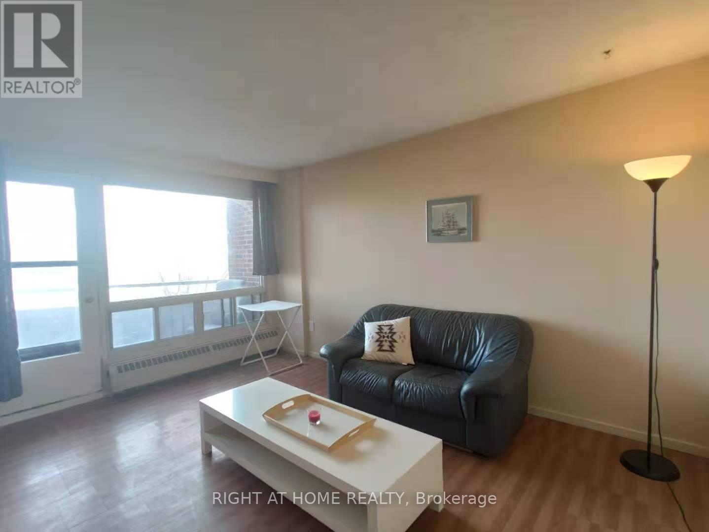A living room with a black leather couch and a white coffee table.