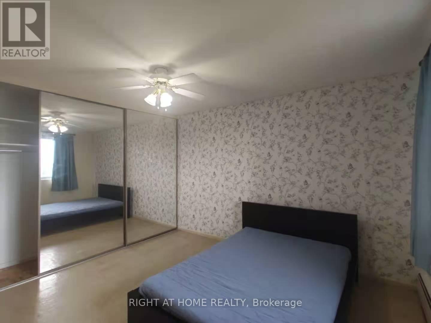 A bedroom with a bed, a ceiling fan, and a wallpapered wall.