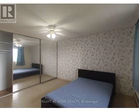 A bedroom with a bed, a ceiling fan, and a wallpapered wall.