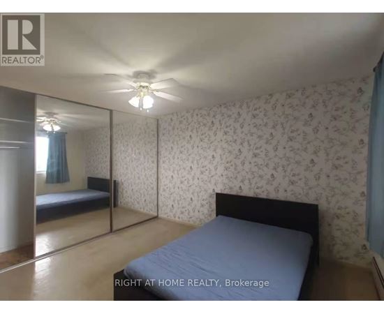 A bedroom with a bed, a ceiling fan, and a wallpapered wall.
