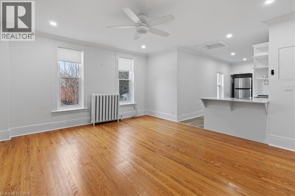 A spacious room with wooden flooring and a ceiling fan.