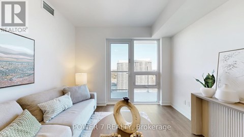 A living room with a grey couch and a large window.